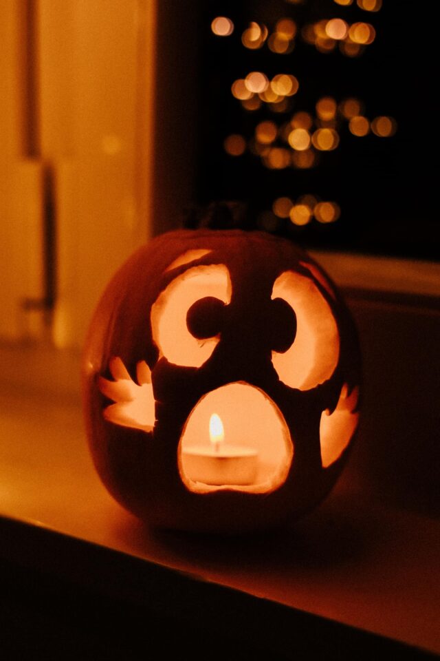 Schielender Halloween-Kürbis mit aufgerissenem Mund und Kerze.