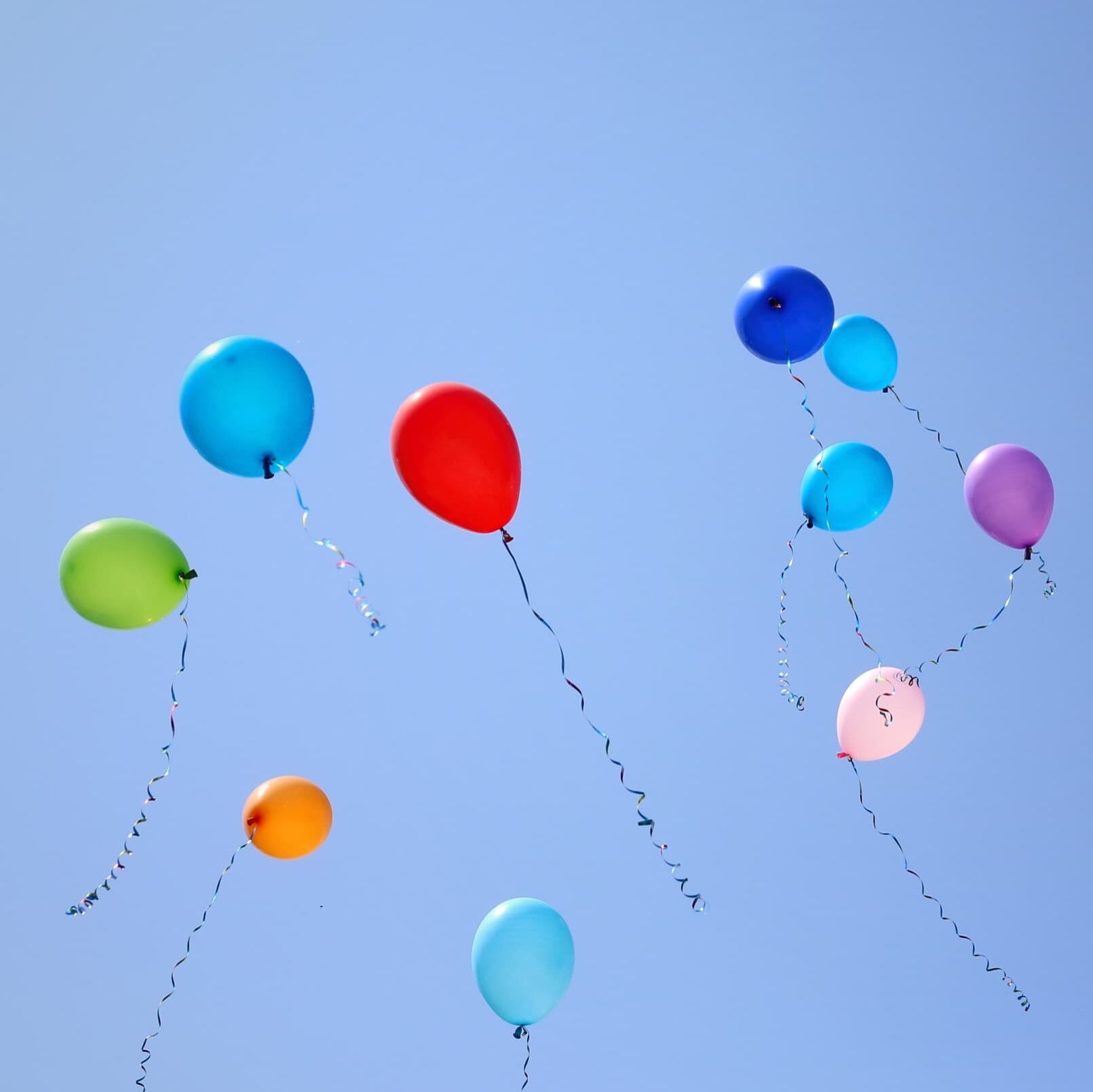 Viele bunte Luftballons vor blauem Himmel