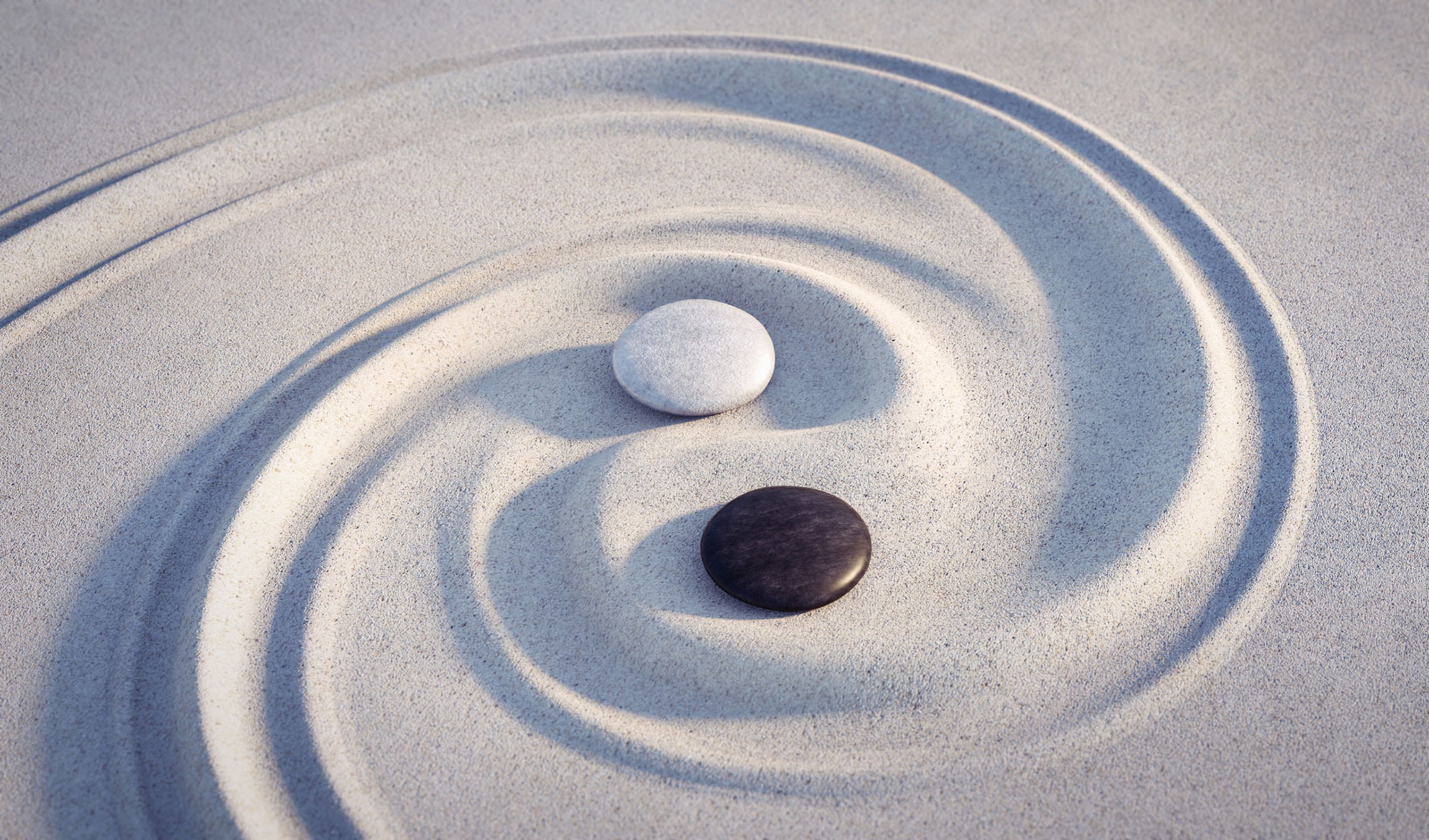 Zwei Steine im Sand mit YinYang-Zeichen